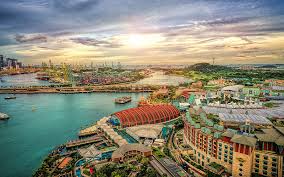 A panoramic view of Sentosa Island’s beach with palm trees, golden sand, and visitors enjoying the sun and sea.