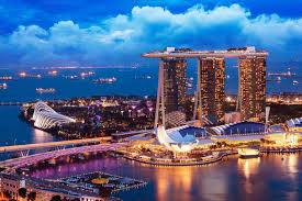 Aerial view of Marina Bay Sands and Gardens by the Bay in Singapore during sunset, with city skyline in the background.