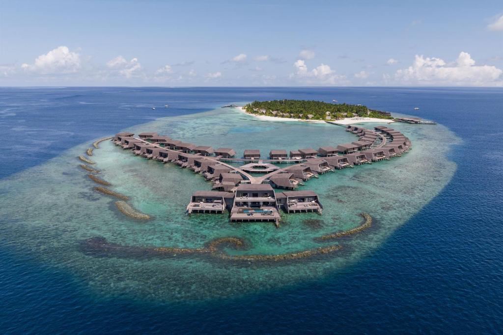 Aerial view of The St. Regis Maldives Vommuli Resort with overwater villas surrounded by turquoise ocean