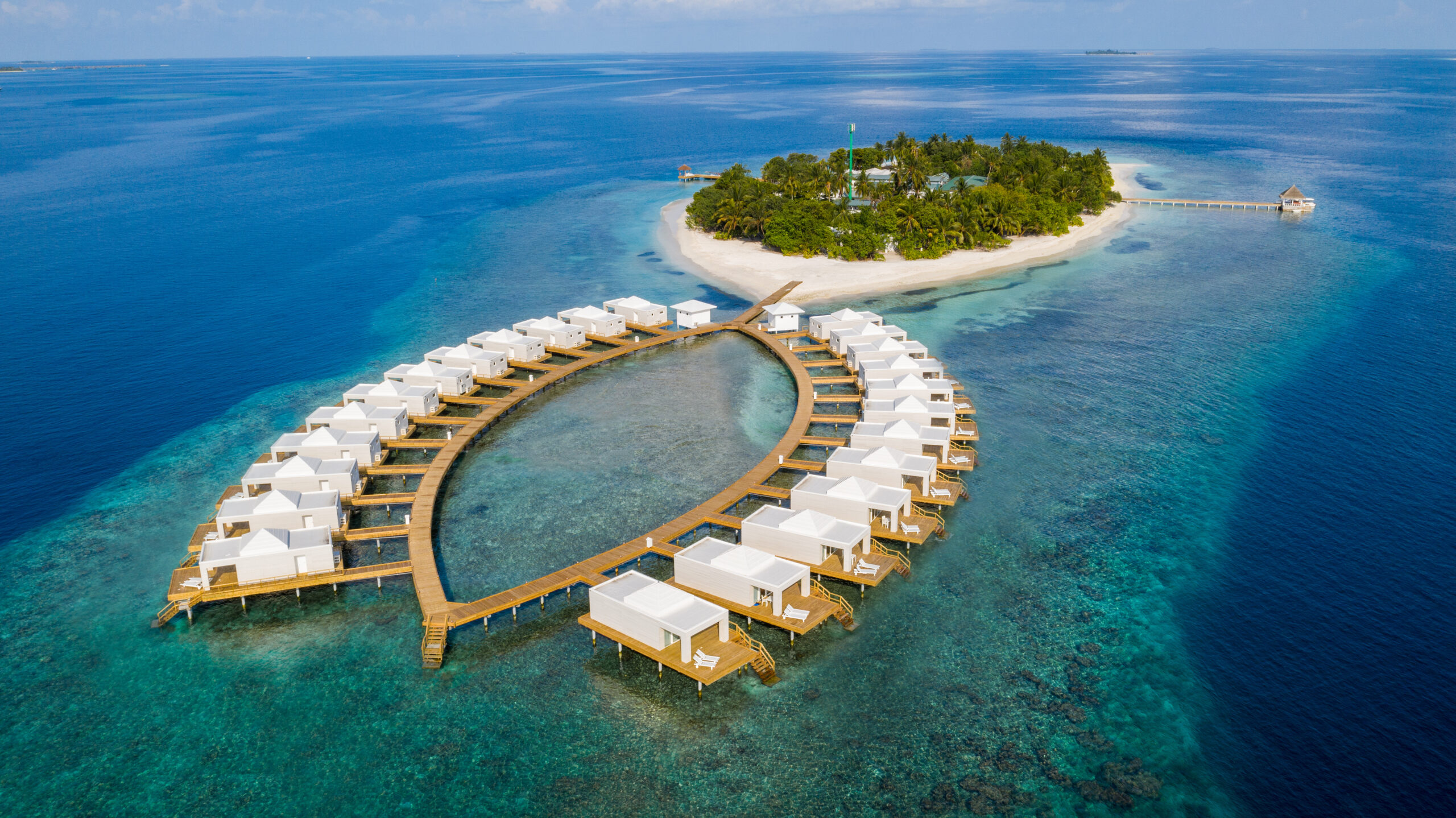 Beachfront view of Sandies Bathala Maldives resort with overwater bungalows and turquoise waters